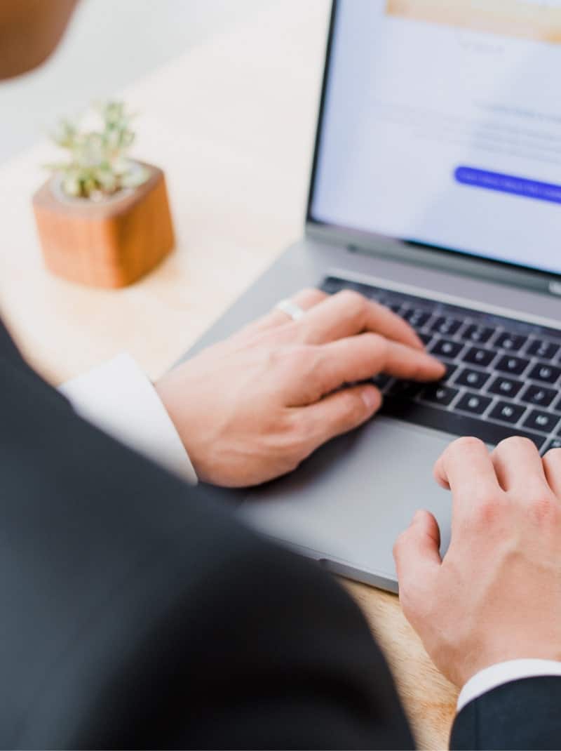 A man in a suit is typing on a laptop